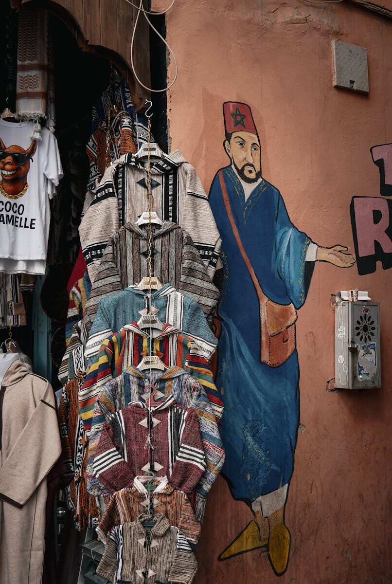 Vibrant market scene in Marrakesh with traditional clothing and street art mural.