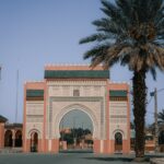 Beautiful Moroccan archway in Rissani with palm trees under a clear blue sky.