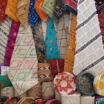 Vibrant Moroccan rugs and cushions on display, showcasing intricate designs and craftsmanship.