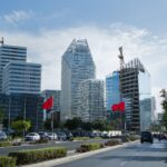 Urban skyline of Casablanca featuring modern architecture and Moroccan flags on a sunny day.