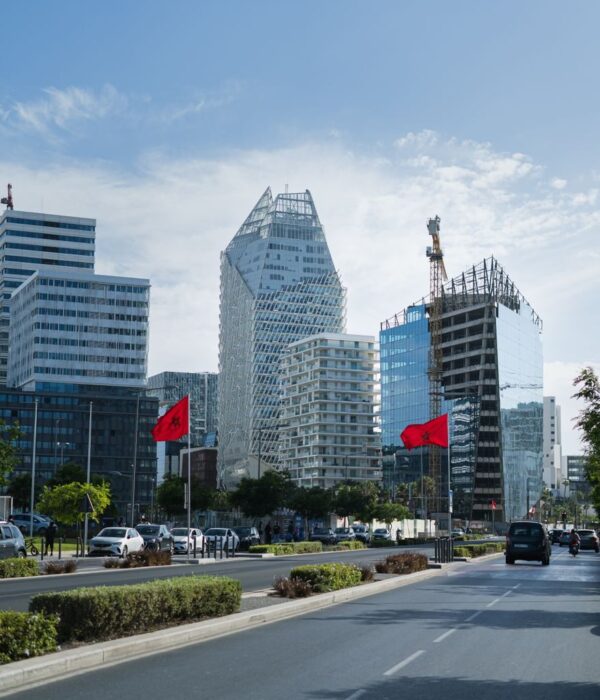 Photo by Morocco Vacation Trips Urban skyline of Casablanca featuring modern architecture and Moroccan flags on a sunny day.